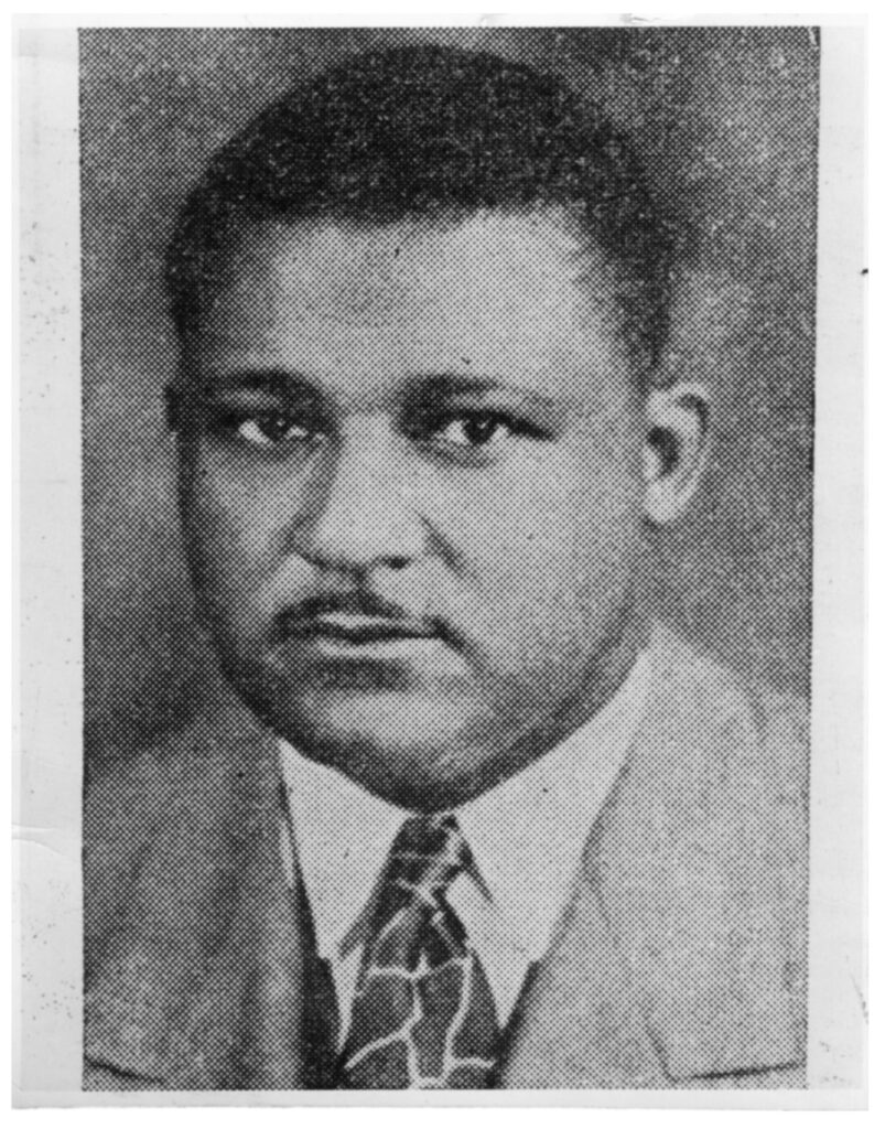 Black and white photo of Friendly Rice, an African American man with round features wearing a light-colored suit and tie and a stern expression